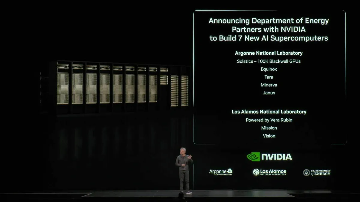 Pildil on mees mustal laval rääkimas. Tema taga on suur ekraan, kus teatatakse, et Energeetikaministeerium koostöös NVIDIA-ga ehitab seitse uut tehisintellekti superarvutit. Ekraani paremal pool on loetletud Argonne'i ja Los Alamose laboratooriumid koos projektide nimedega. Vasakul pool on näha arvutiklastrit või serveririiulit. Ekraanil all on NVIDIA ja partnerlaborite logod.